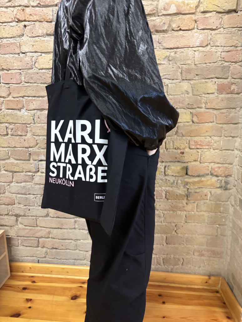 Person mit Tasche und Logo der Karl-Marx-Straße